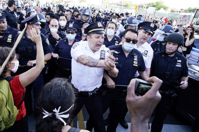 A NYPD police officer sprays protesters as they clash during a march against the death in Minneapolis police custody of George Floyd, in the Brooklyn borough of New York City, U.S., May 30, 2020. REUTERS/Eduardo Munoz     TPX IMAGES OF THE DAY